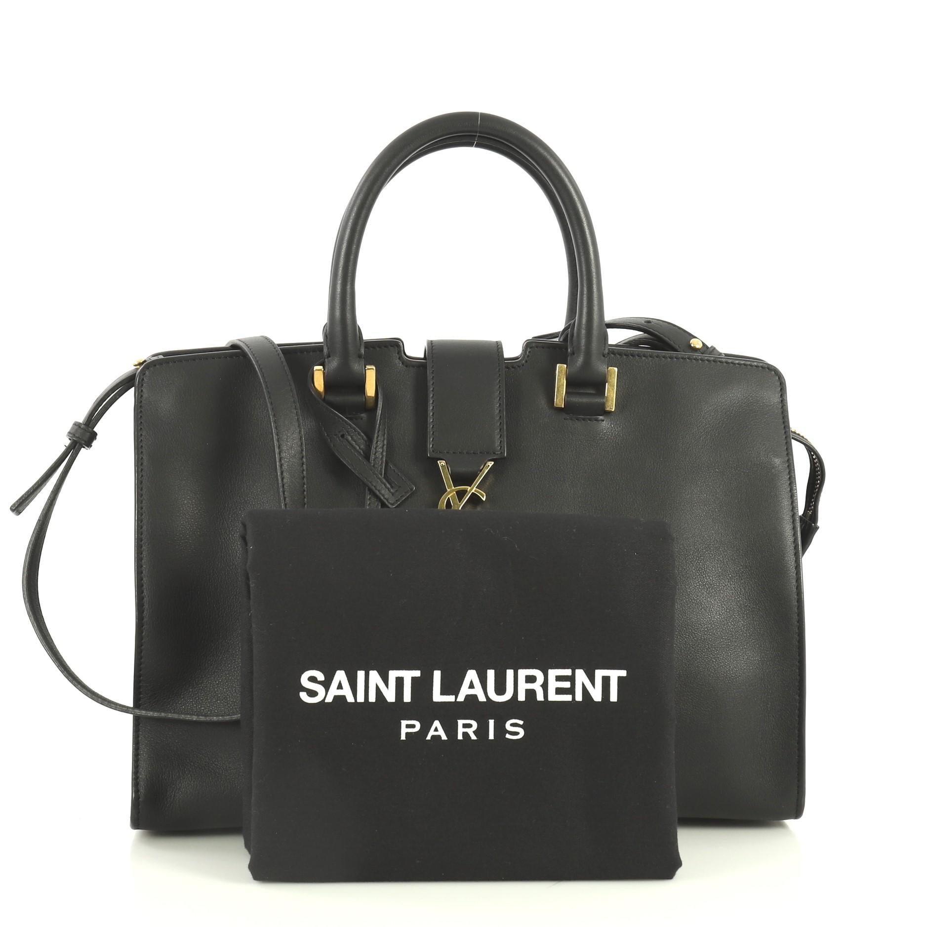 This Saint Laurent Monogram Cabas Leather Small, crafted in black leather, features dual rolled handles, leather tab with YSL logo, and gold-tone hardware. Its zip closure opens to a black suede and leather interior with zip and slip pockets.