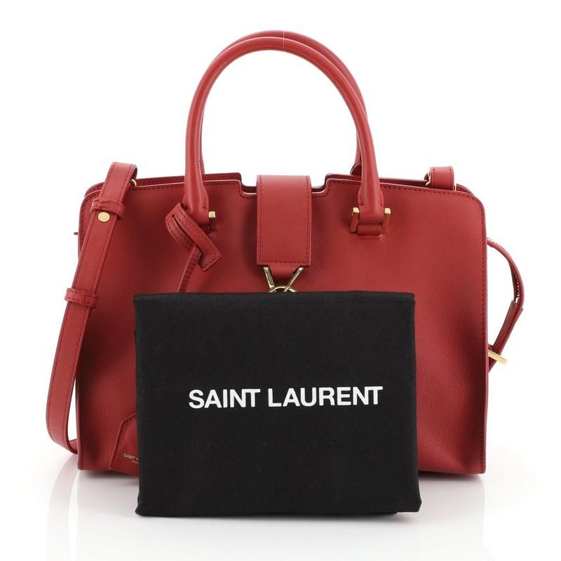 This Saint Laurent Monogram Cabas Leather Small, crafted in red leather, features dual rolled handles, leather tab with YSL logo, and gold-tone hardware. Its zip closure opens to a red suede and leather interior with zip and slip pockets.