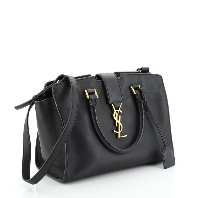 This Saint Laurent Monogram Cabas Leather Small, crafted in black leather, features dual rolled handles, leather tab with YSL logo, and gold-tone hardware. Its zip closure opens to a black suede and leather interior with zip and slip pockets.
