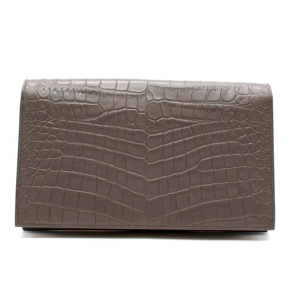 Yves Saint Laurent Grey Croc Embellished Clutch

- Croc embossment on the body of the bag
- Silver YSL in the middle by the opening
- Rectangle shape
- Saint Laurent silver print on the inside
- Black canvas lining inside with a cardholder