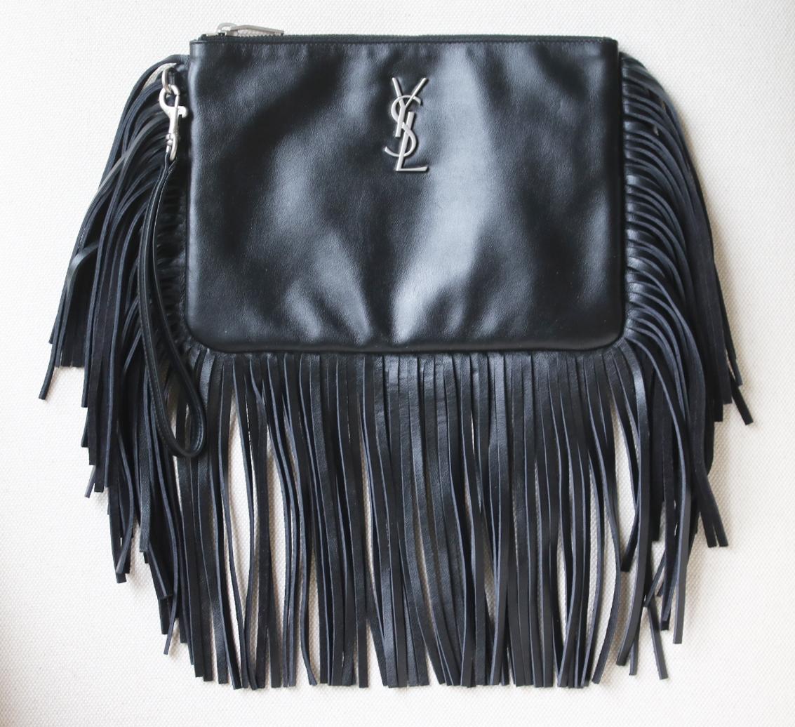 Saint Laurent calfskin leather clutch bag. Trimmed in long fringe. Zip top closure. YSL logo lettering. Black leather. Made in Italy. Does not come with a dustbag or box.

Dimensions: L 9 x H 6.5 x D 1 inches
Removable wrist strap drop: 6