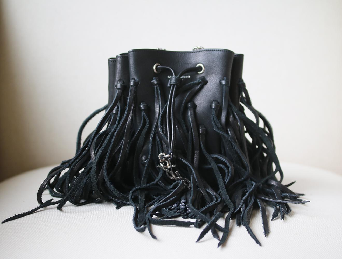 Perfect as part of a chic bohemian look, Saint Laurent's leather 'Monogramme Bourse' bucket bag is finished with fringing. Sized to fit just your essentials perfectly, this mini style is decorated with the brand's signature 'YSL' plaque in silver.