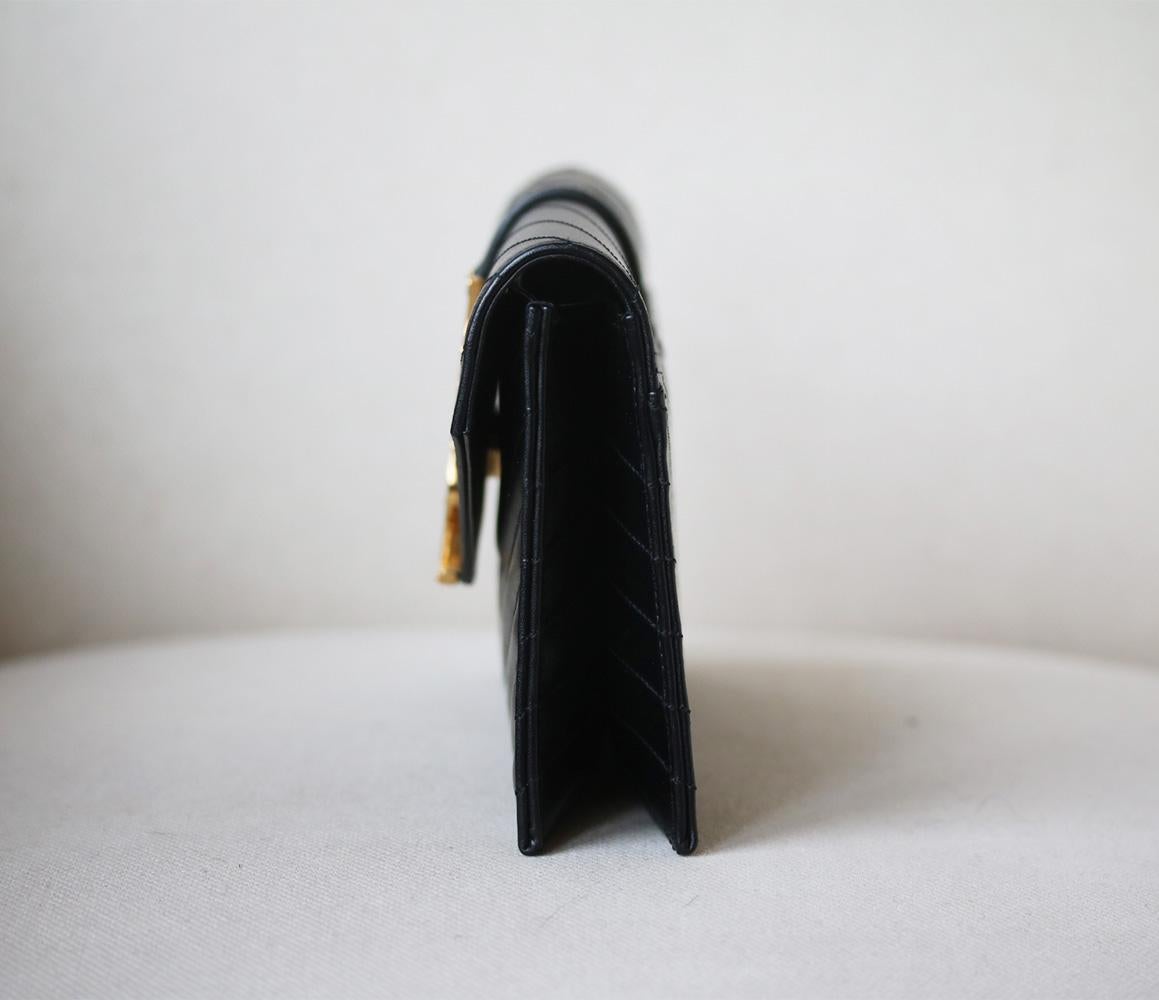 Saint Laurent black monogram envelope clutch bag. This stylish clutch is made from black leather and features gold tone hardware including a YSL monogram logo detailing. The clutch features monogram stitch detailing and has a magnetic snap closure.