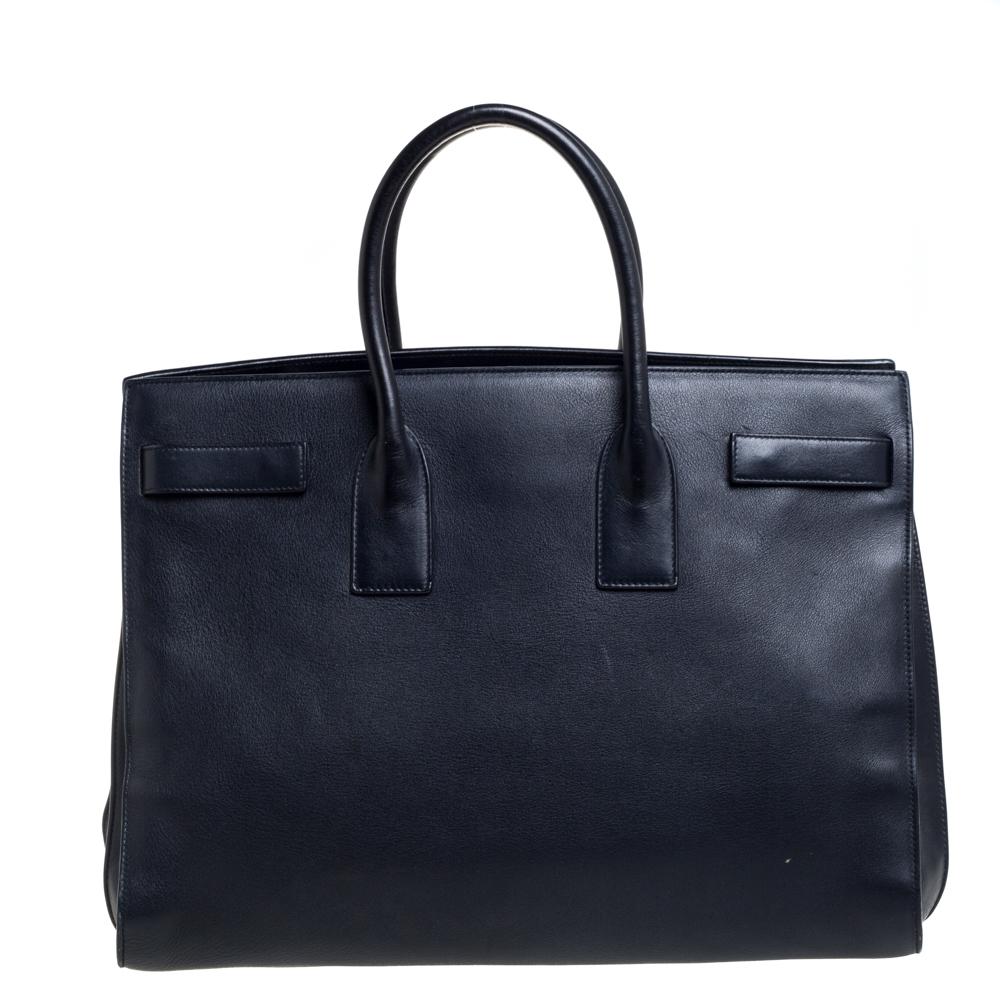 This Sac de Jour tote by Saint Laurent has a structure that simply spells sophistication. Crafted from navy blue leather, the bag is held by double-top handles. The tote comes with a suede-lined interior with enough space to store your necessities