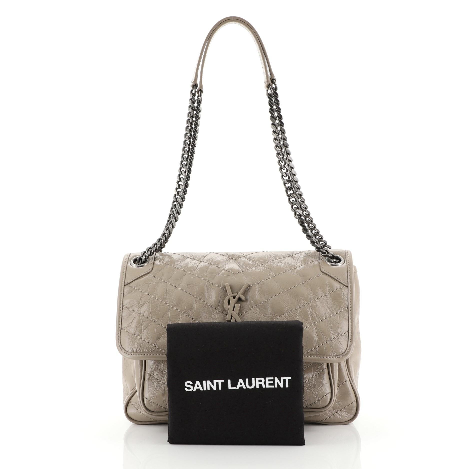 This Saint Laurent Niki Chain Flap Bag Matelasse Chevron Leather Medium, crafted in neutral matelasse chevron leather, features chain link shoulder straps with leather pads, frontal flap with YSL monogram detail, and aged silver-tone hardware. Its