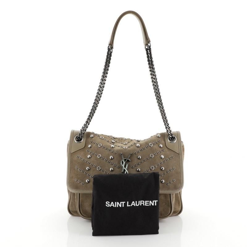 This Saint Laurent Niki Chain Flap Bag Studded Suede Medium, crafted in brown suede, features dual chain and leather shoulder strap, stud and grommet trims, signature YSL logo and aged silver-tone hardware. Its clasp closure opens to a black fabric