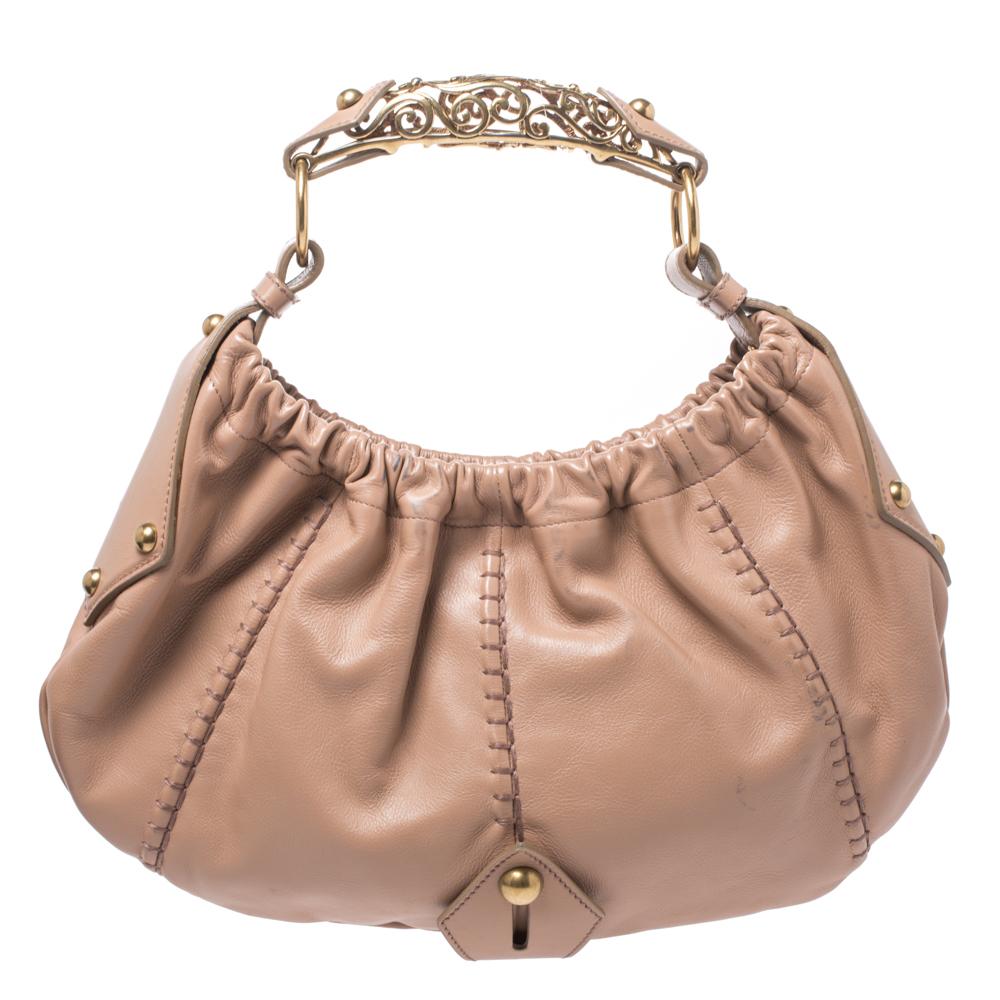 You will love to have this Saint Laurent Mombasa hobo. Crafted from classic nude beige leather and held by a beautiful metal handle, it is a beauty. Fastened by a snap magnetic button, the interior is lined with satin and sized to house your