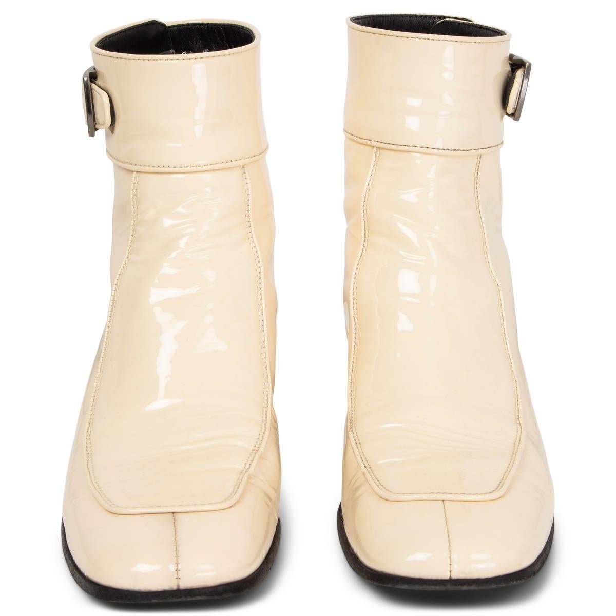 100% authentic Saint Laurent Miles square-toe ankle boots crafted in cream smooth patent leather that are distressed by hand to create a subtle crinkled effect and decorated with a simple gunmetal buckle above a low stacked heel. Opens with a zipper