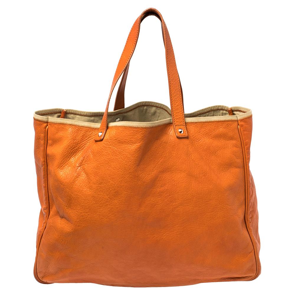 We all need one tote that will not only help assist our style but also be versatile enough for all our outings. Here's one from Saint Laurent. It comes finely crafted from leather in a vibrant orange shade. The dual handles and a spacious fabric