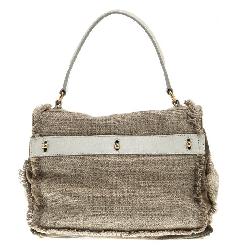 The beige Muse Two satchel from Saint Laurent Paris has an innovative design and is crafted in fabric and suede. The bag has frayed edges and white suede trims at the front, base and back panel. The flap opens to a smooth suede lined interior that