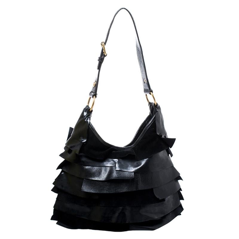 Show your elegant fashion sense by carrying this Saint Laurent Paris ‘St. Tropez’ shoulder bag. Crafted of black leather with signature tiered ruffle panels, this bag features a long shoulder strap that is enhanced with gold-tone buckles, studs and
