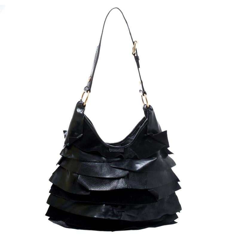 Show your elegant fashion sense by carrying this Saint Laurent Paris ‘St. Tropez’ shoulder bag. Crafted of black leather with signature tiered ruffle panels, this bag features a long shoulder strap that is enhanced with gold-tone buckles, studs and
