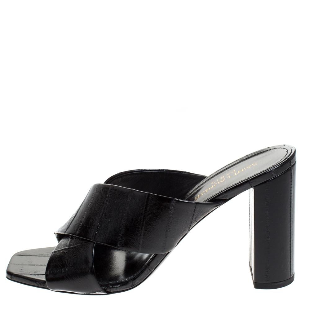 Charm your way to all your social gatherings in this pair of mules from Saint Laurent Paris. Crafted from black textured leather, they carry a feminine design with criss-cross straps and beautiful block heels detailed with the YSL