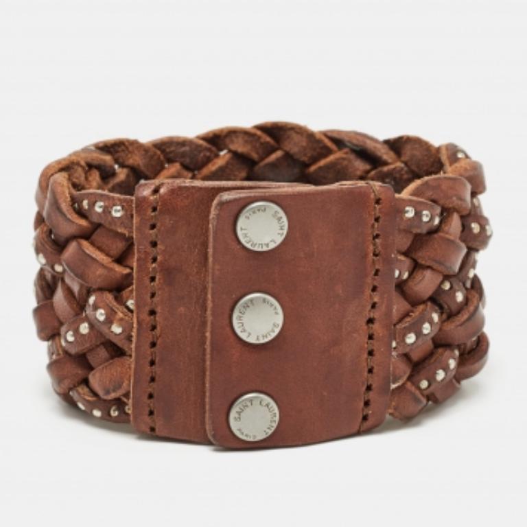 Para acompañar todas tus salidas, día tras día, Saint Laurent te trae esta pulsera pulcramente trenzada en marrón  cuero. La pulsera se completa con detalles en tono plateado. Perfecta para llevar a diario, ¡esta pulsera es una compra obligada!