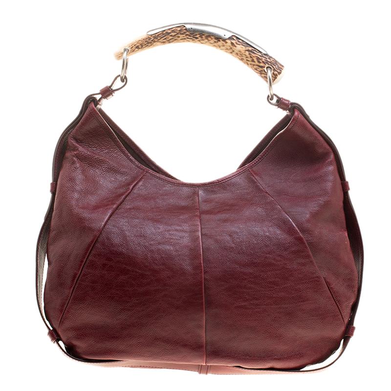 Saint Laurent Paris has infused interesting, unique details in this notable Mombasa hobo. It is made of burgundy leather with protective leather trim outlining the bag. A signature of the Mombasa style, the shoulder strap features a horn shoulder