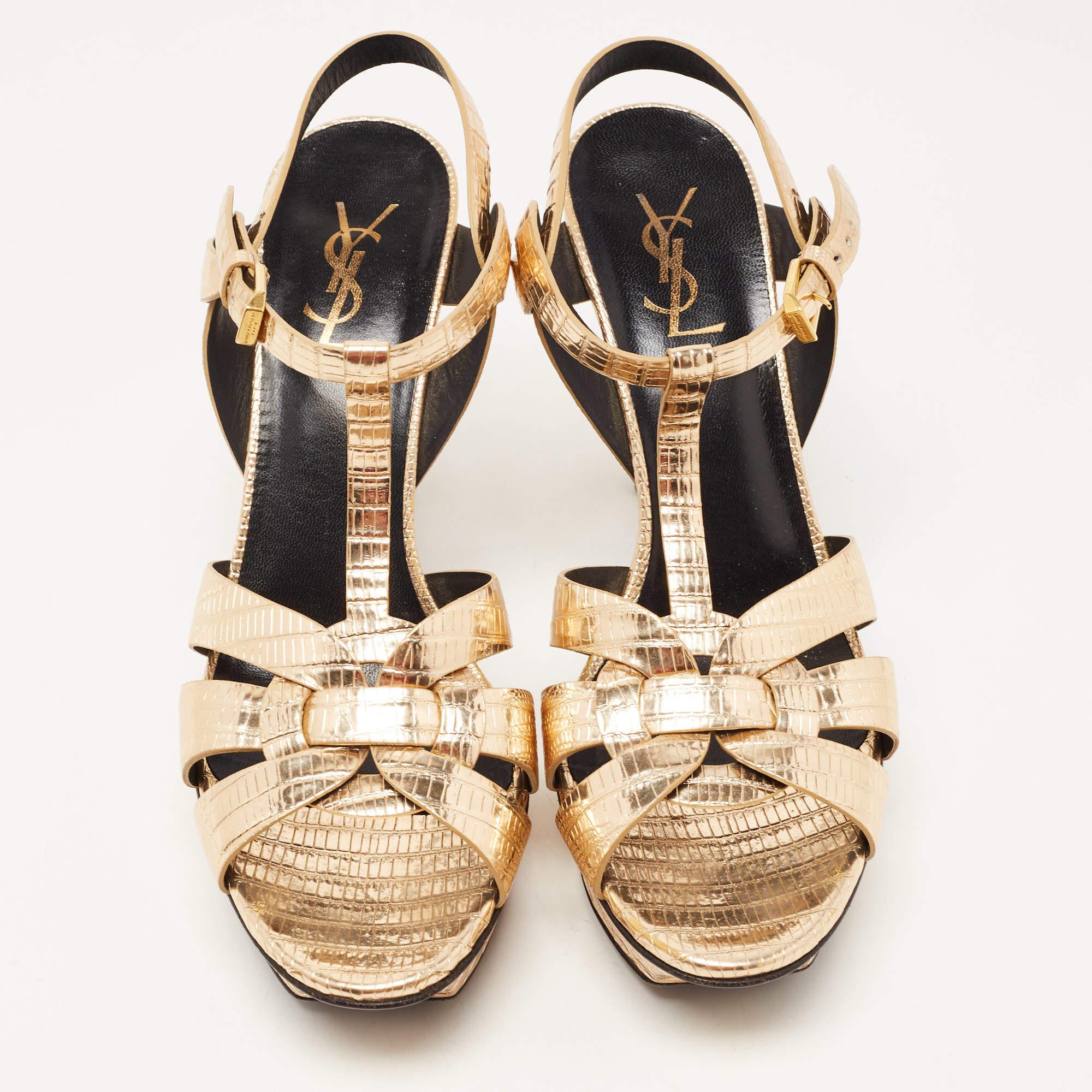The fashionista in you will fall in love with these Saint Laurent Tribute sandals. They are made from lizard-embossed leather with intertwined straps on the vamps and ankle buckle closure. The gold-tone hardware, 11cm heels, and platform give this