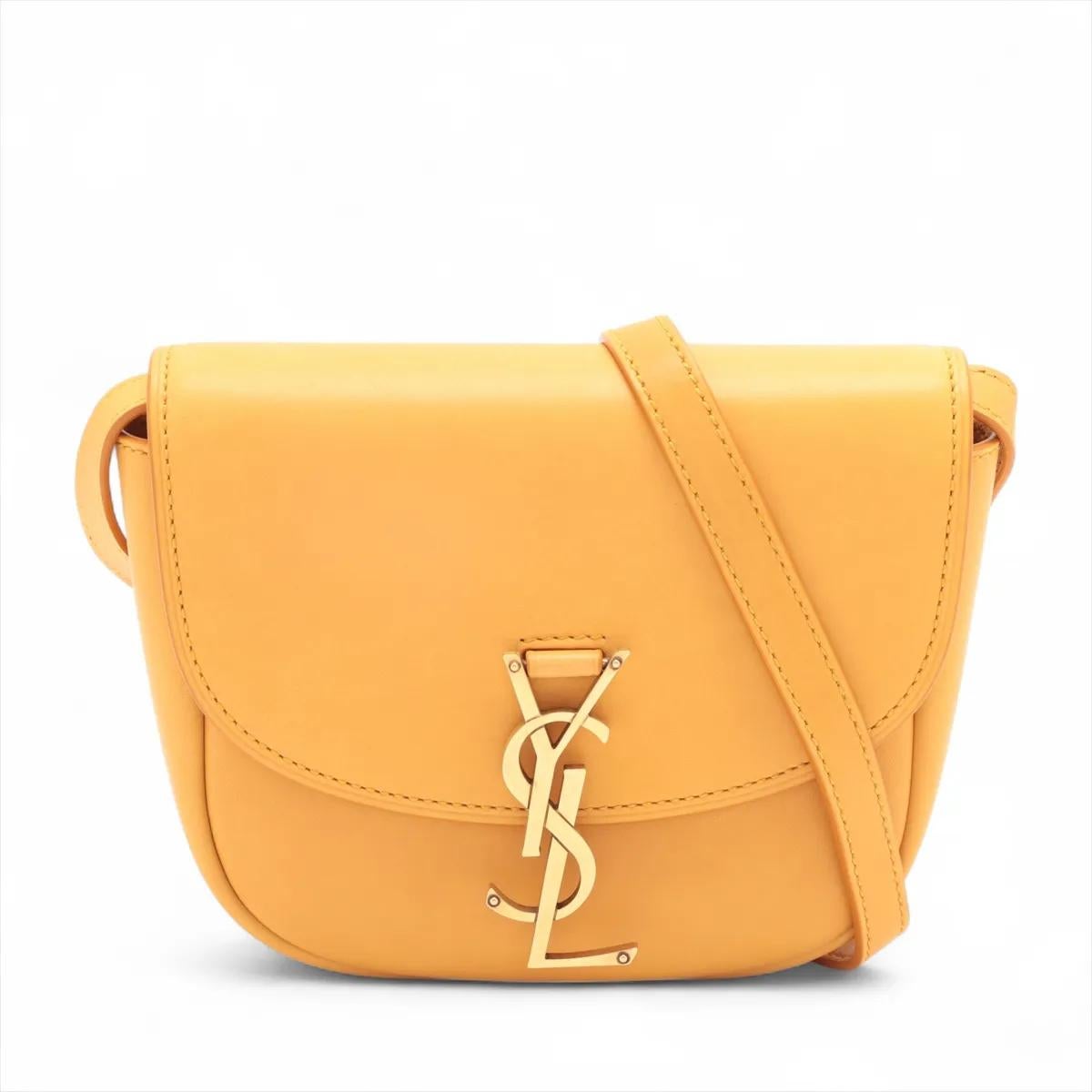 La borsa a tracolla Kaia in pelle gialla di Saint Laurent Paris è un accessorio vibrante ed elegante che eleva senza sforzo qualsiasi look. Realizzata in pelle liscia, presenta una patta arrotondata ornata dall'iconico Monogram YSL in metallo