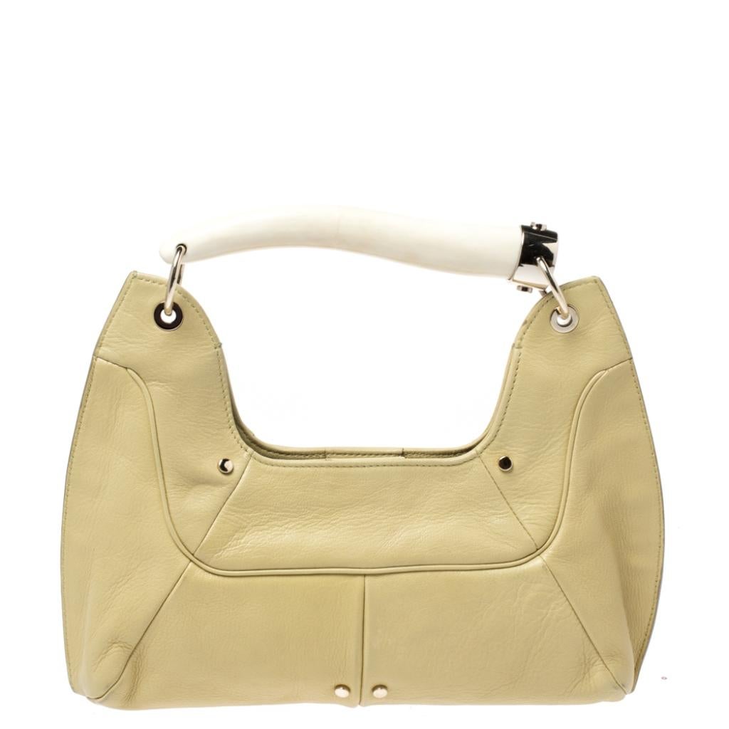 You will love to have this Saint Laurent Paris Mombasa hobo. Crafted from light yellow leather and held by a horn-shaped handle, it is a beauty. Fastened by a snap magnetic button, the interior is lined with satin to house your essentials with