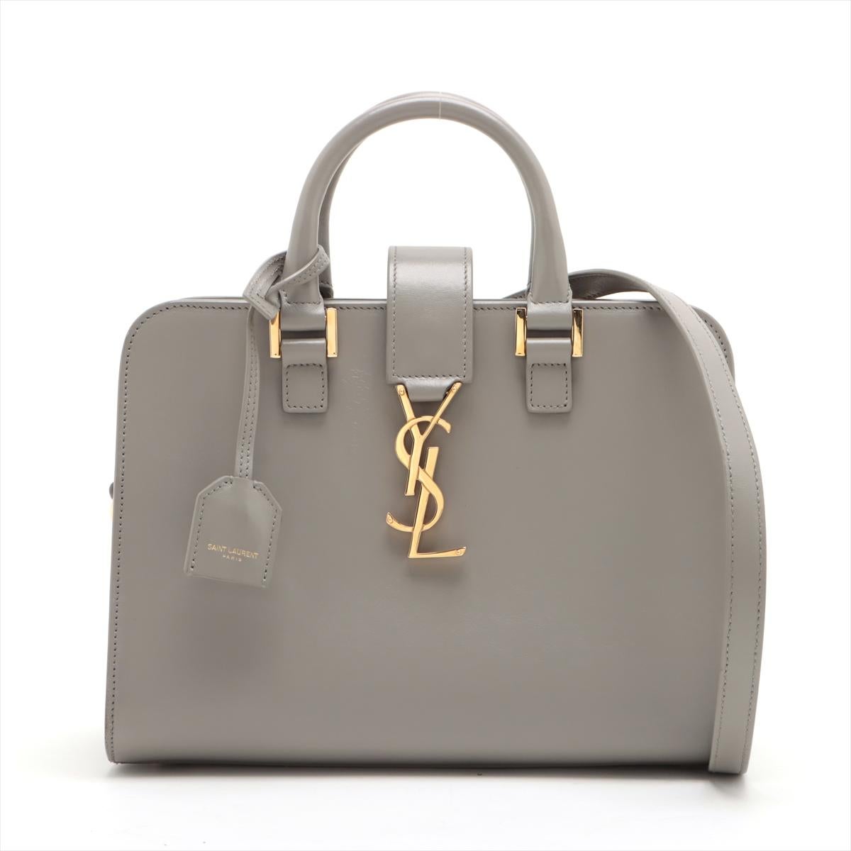 The Saint Laurent Paris Navy Cabas Leather Two-Way Handbag in Grey is a sophisticated and versatile accessory that exudes understated luxury. Crafted from high-quality leather, the handbag features a sleek and structured silhouette with minimalistic