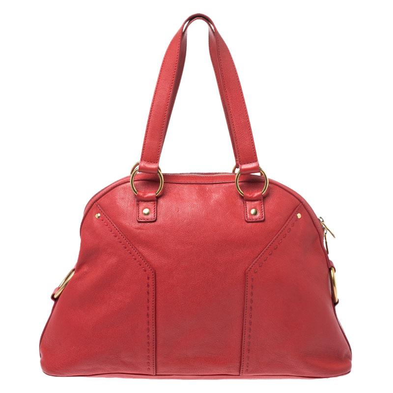 This Saint Laurent Muse satchel is perfect for everyday use. It has been meticulously crafted from leather and enhanced with gold-tone hardware. This red-colored satchel has two handles and a zipper which opens to a roomy satin interior capable of