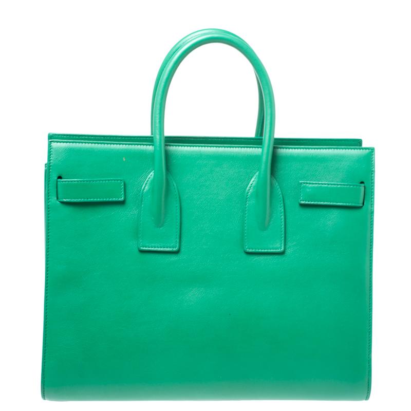 This Sac de Jour tote by Saint Laurent Paris has a structure that simply spells sophistication. Crafted from green leather, the bag is held by double top handles. The tote comes with a suede-lined interior with enough space to store your necessities
