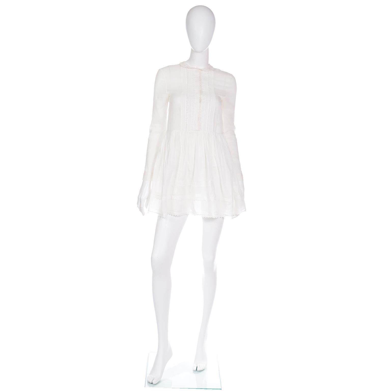 This is a lovely Saint Laurent Paris lightweight white cotton babydoll style tunic blouse with a variety of fine lace trim. This top is in a breathable semi-sheer fabric and it has lace detailing at the Peter Pan collar, hemline, and bodice front.