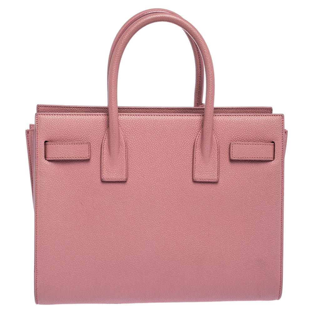 This Sac de Jour tote by Saint Laurent has a structure that simply spells sophistication. Crafted from pink leather, the bag is held by double top handles. The tote comes with a canvas-lined interior with enough space to store your necessities and