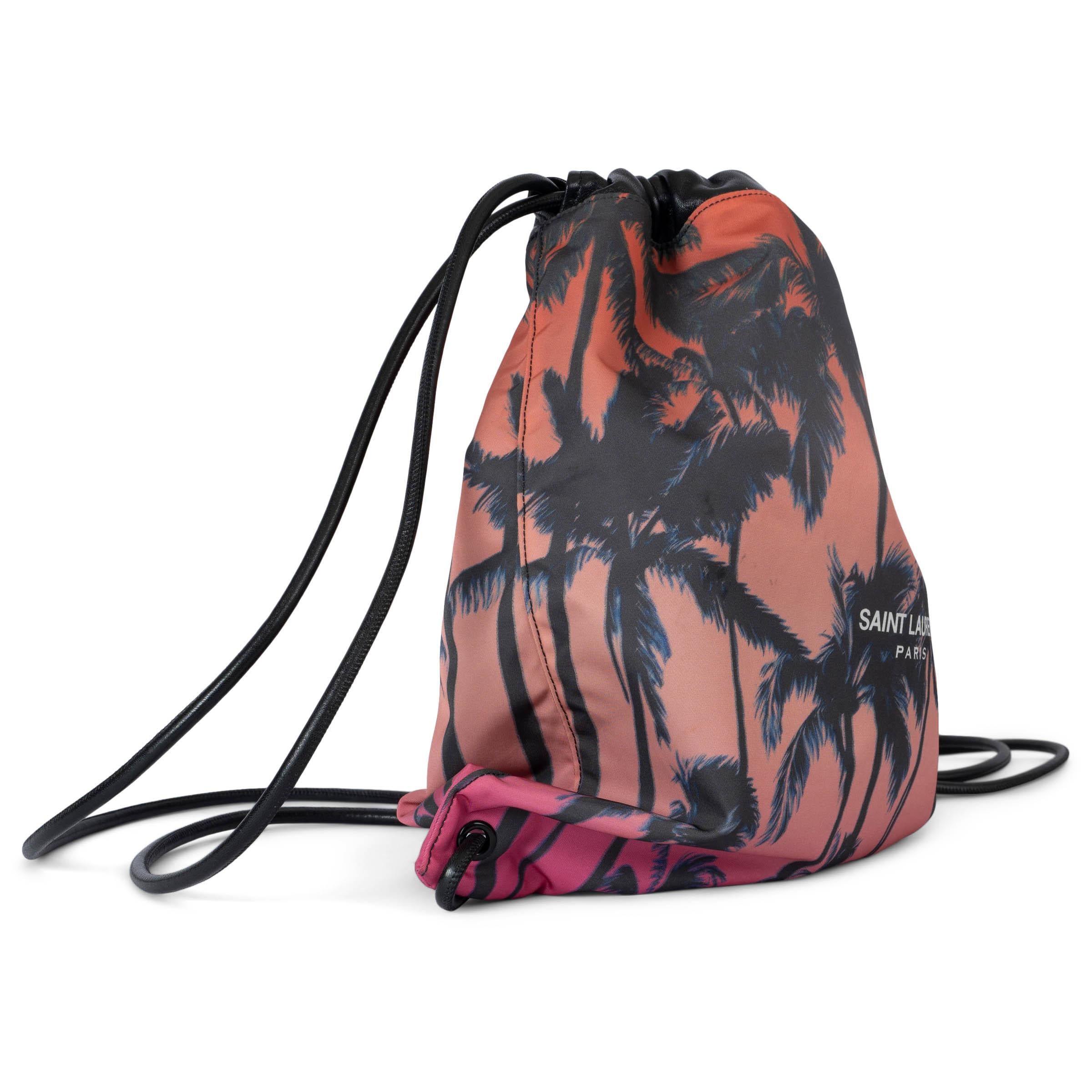 100% authentic Saint Laurent Palm Tree Teddy drawstring backpack in gradient pink, red and black nylon. The design features black leather trim and shoulder straps. Lined in black canvas with one zipper pocket against the back. Has been carried and