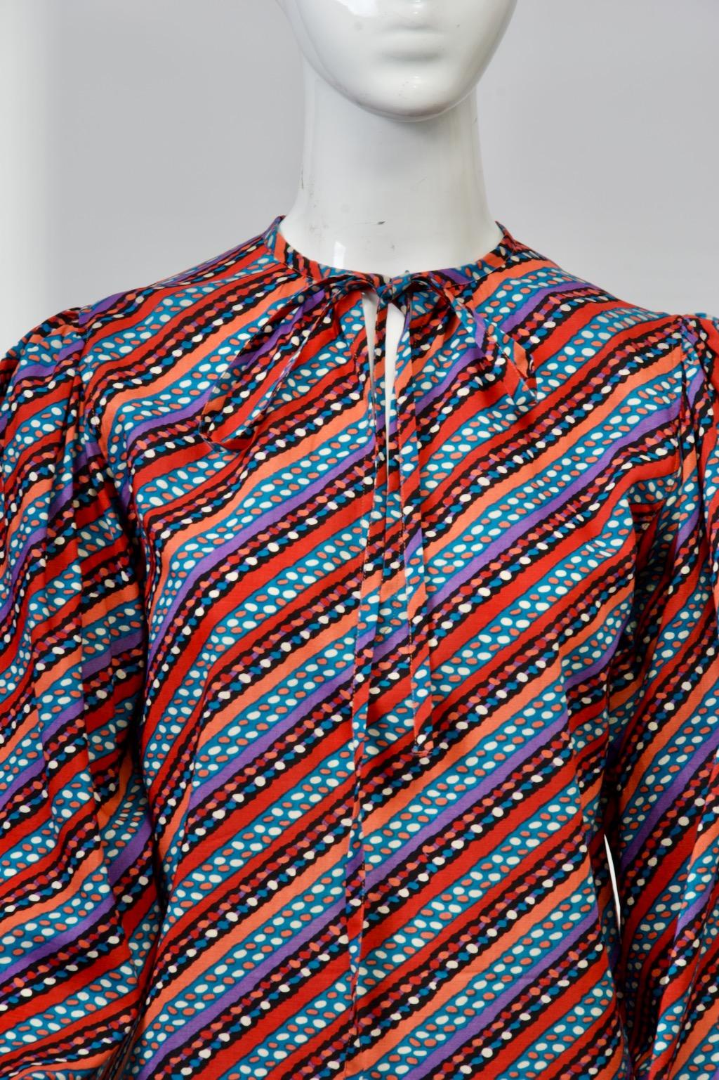 Saint Laurent rive gauche blouse, c. 1970s, crafted of a diagonal print alternating between solid stripes with those containing small ovals, all in multicolors of rust, orange. purple, blue, black, and white. The blouse has a straight cut and