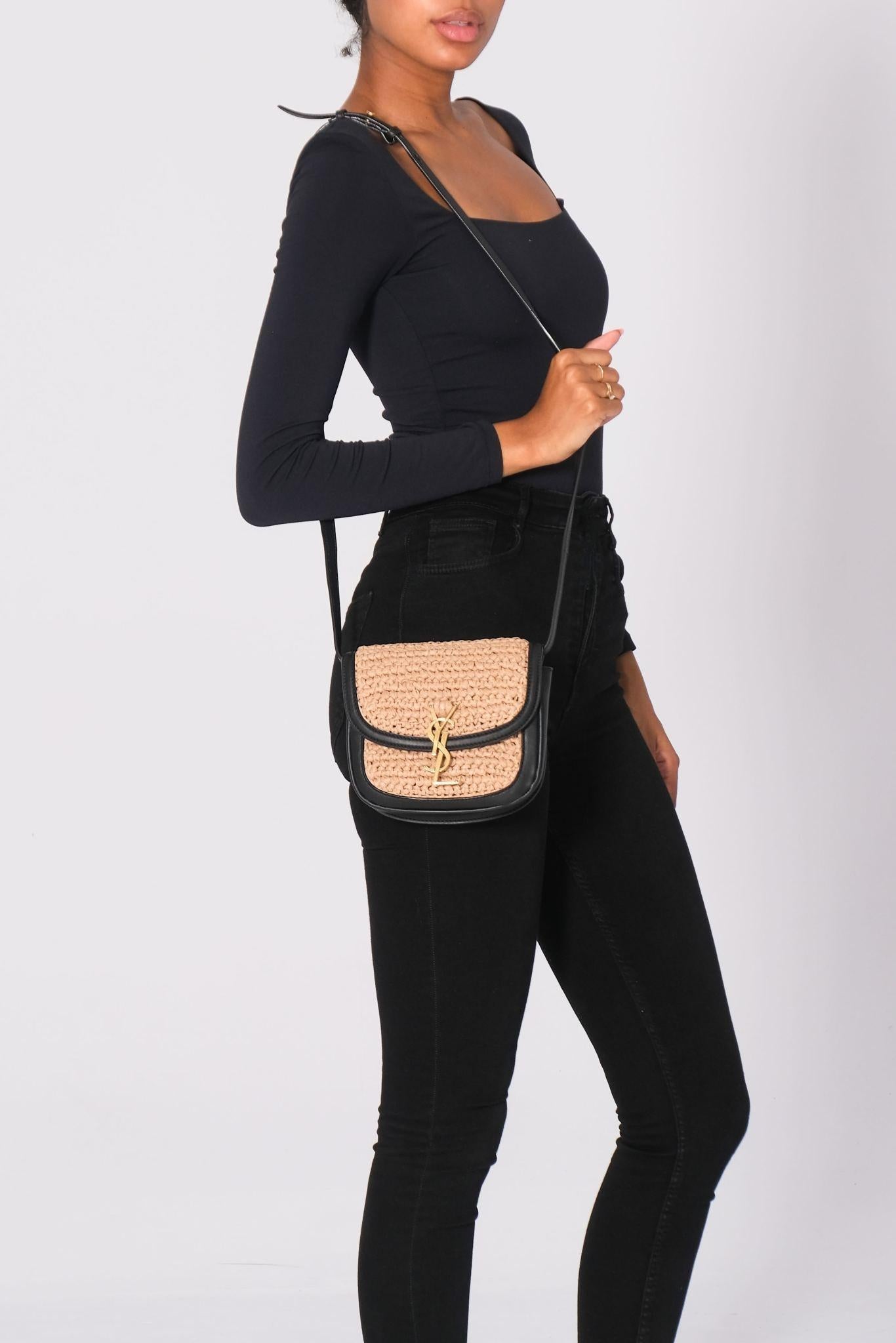 This shoulder bag is made of raffia in beige with black leather trim and details. The bag features an adjustable crossbody strap and brass hardware. The flap with snap closure opens to a compact black fabric interior with a pocket. Outlet.

Color: