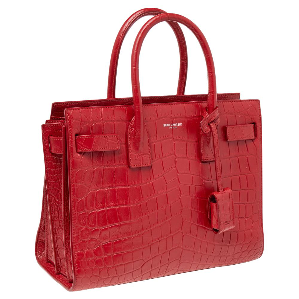 This Sac de Jour tote by Saint Laurent has a structure that simply spells sophistication. Crafted from red croc-embossed leather, the bag is held by double top handles. The tote comes with a leather-lined interior with enough space to store your