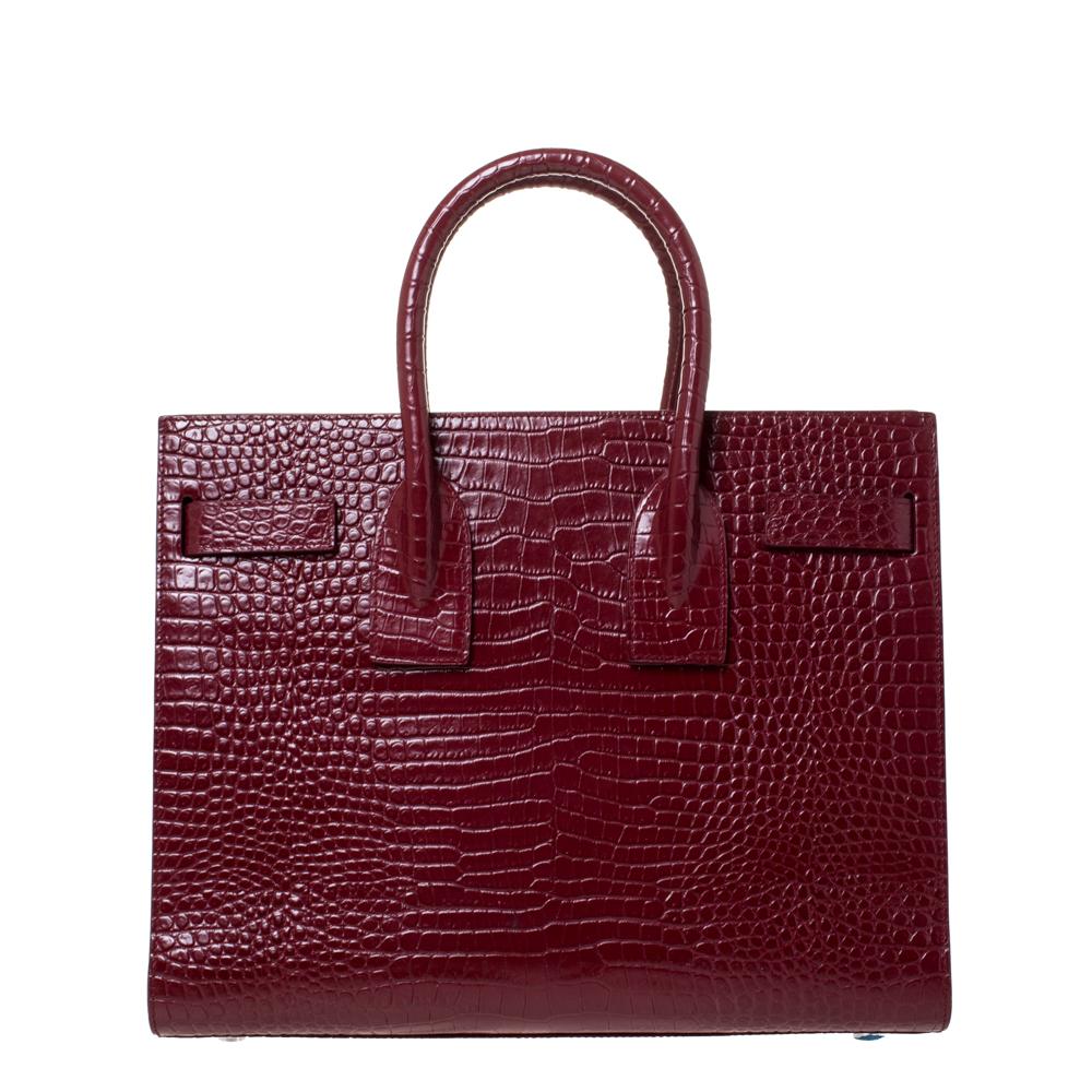 This Sac de Jour tote bag by Saint Laurent has a sophisticated look. Crafted from croc-embossed leather, the bag has dual round handles and protective metal feet. The tote comes with a canvas-lined interior that has enough space to store your daily