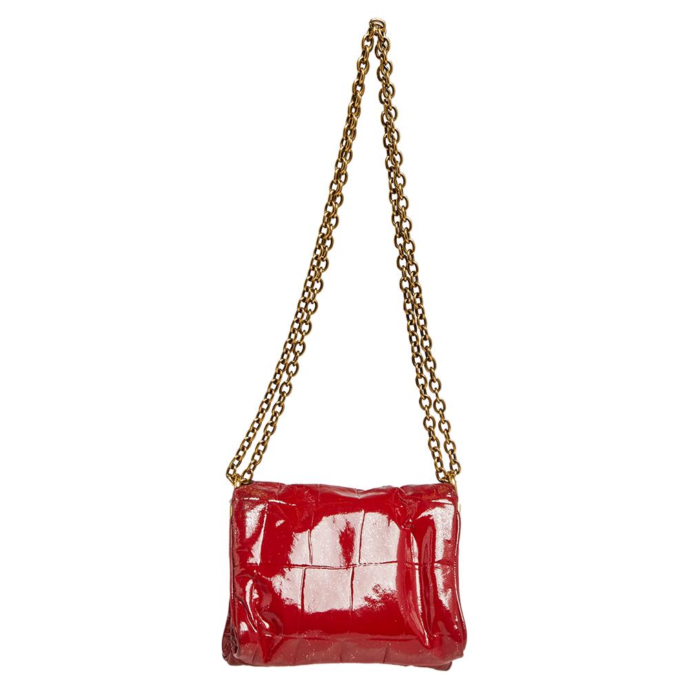 This Saint Laurent crossbody bag presents the label's artistry in fine craftsmanship and classic designs. Made of patent leather, it features a red shade, a shoulder chain, and a front flap that opens to reveal a satin interior for your