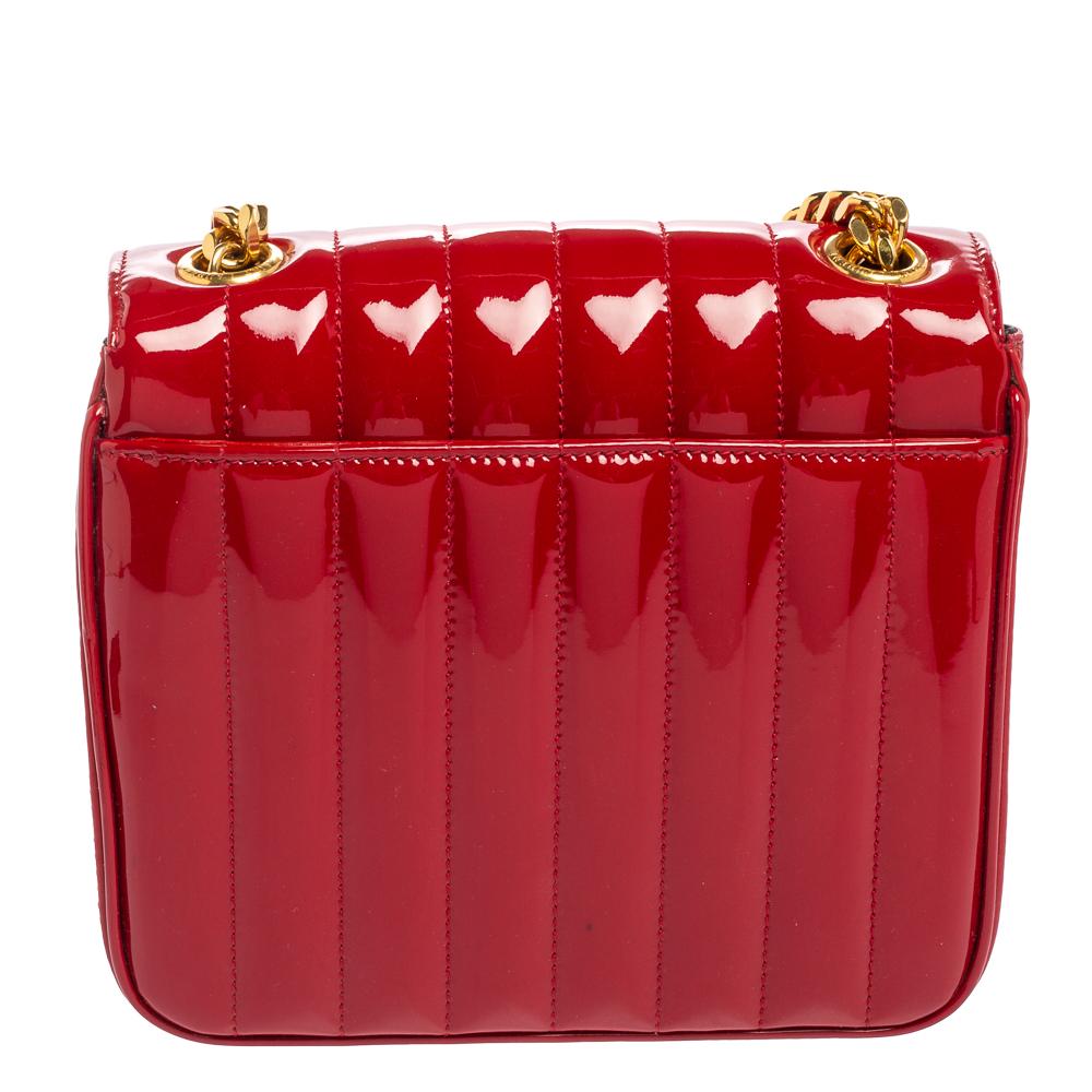 This Saint Laurent Vicky bag has been exquisitely crafted in Italy and made from quilted patent leather. It is equipped with a leather-lined interior that is enclosed with a flap. The exterior features signature elements like the YSL logo in