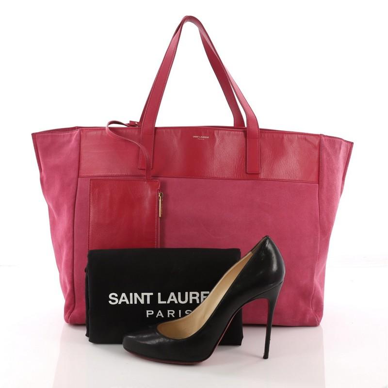This Saint Laurent Reversible East West Shopper Tote Leather, crafted from reversible pink suede, features dual-flat leather handles, protective base studs, and gold-tone hardware. Its wide top opens to a reversible pink leather interior. **Note: