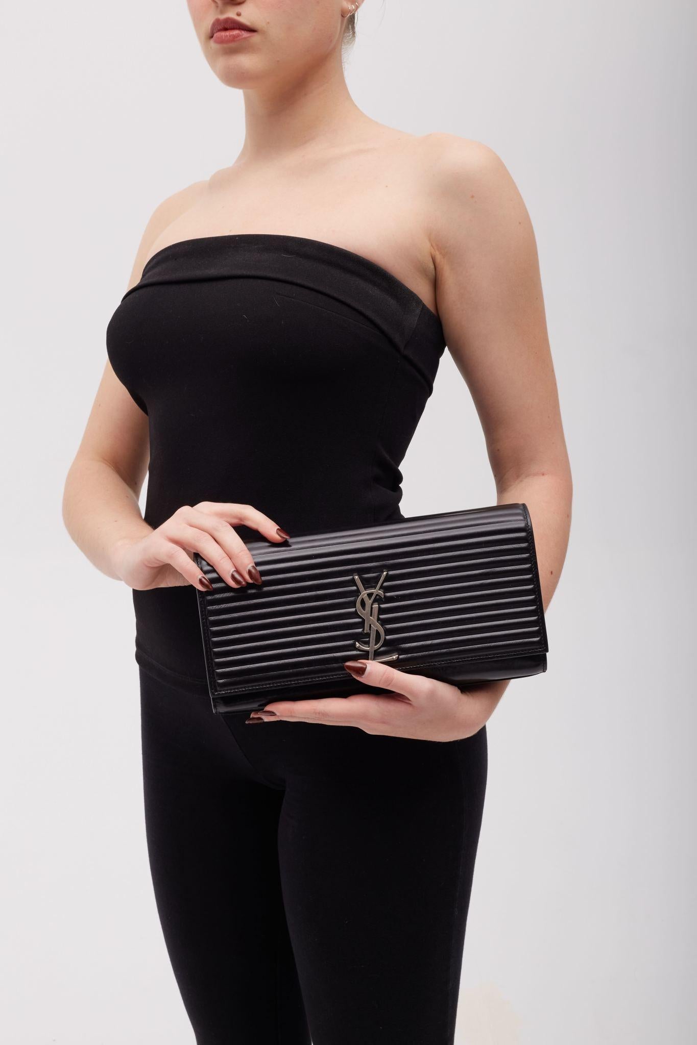 This clutch is made of smooth polished calfskin leather in Black. The clutch features a quilted lining texture and an aged Silver classic YSL monogram on the from flap. The flap opens to a black fabric interior with a small flat pocket

Color: Black