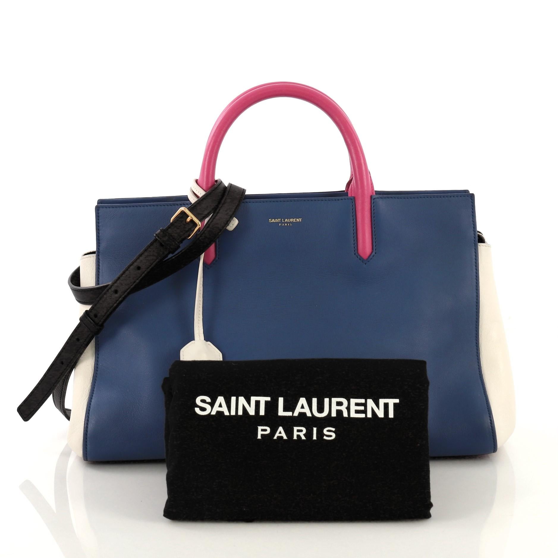 This Saint Laurent Rive Gauche Cabas Leather Small, crafted from blue and white leather, features dual rolled leather handles, protective base studs, side snap buttons, and gold-tone hardware. Its zip closure opens to a black suede interior with