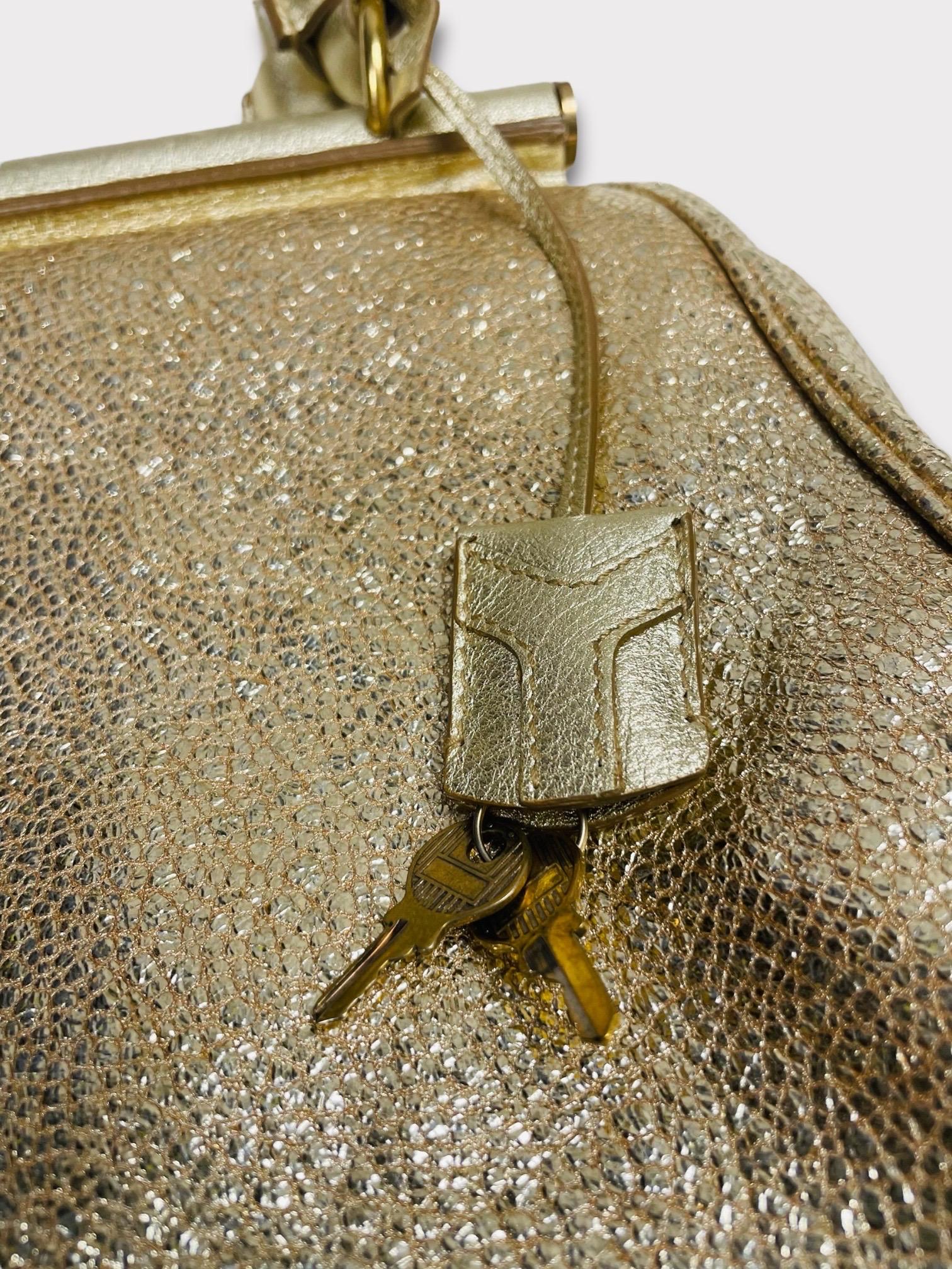 This Yves Saint Laurent Majorelle Bag will add a glamorous touch to your look. It comes in a metallic gold leather exterior accented with gold-toned hardware. This bag features rolled leather handles and feet at the base. The top zip closure opens
