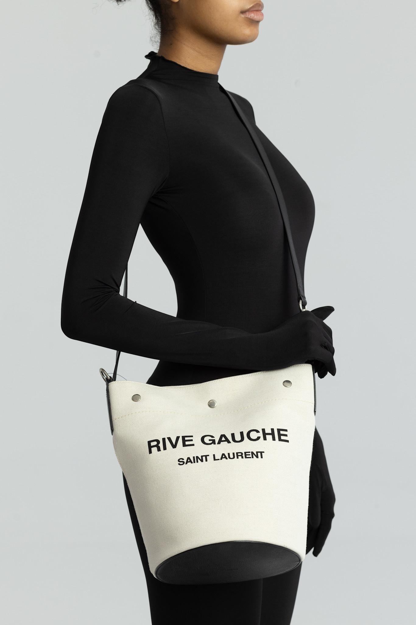 SAINT LAURENT RIVE GAUCHE TUSCANY WHITE LINEN BUCKET BAG

This bucket bag is made of crisp linen and edged with rich leather trim. It is embroidered with logo detail across the front and its interior has one main compartment with a removable