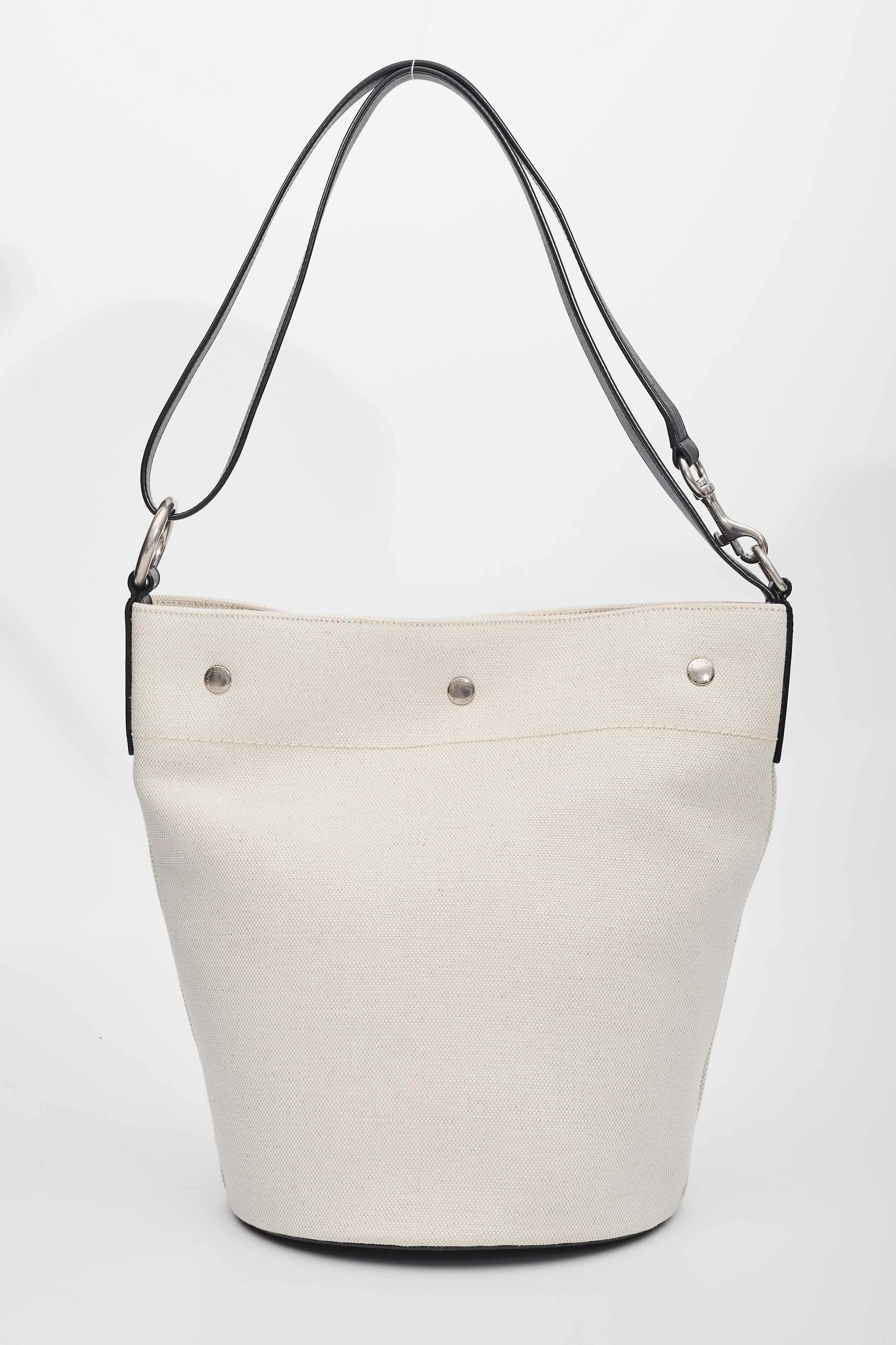 This bucket bag is made of crisp linen and edged with rich leather trim. It is embroidered with logo detail across the front and its interior has one main compartment with a removable zippered pouch. Featuring leather trim and snap button