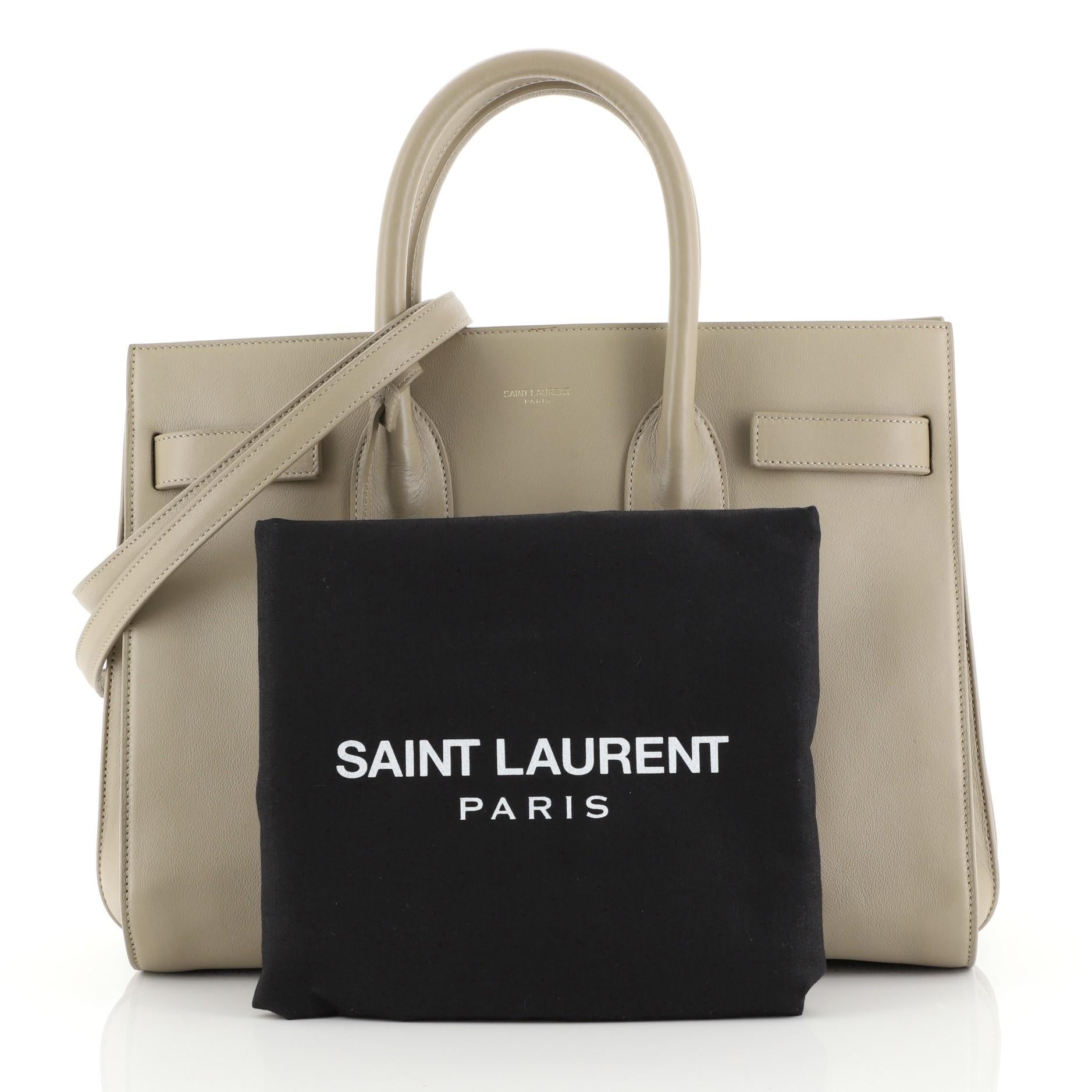 This Saint Laurent Sac de Jour Bag Leather Small, crafted from neutral leather, features dual rolled leather handles, protective base studs, and gold-tone hardware. It opens to a neutral suede and black fabric interior with middle zip compartment.