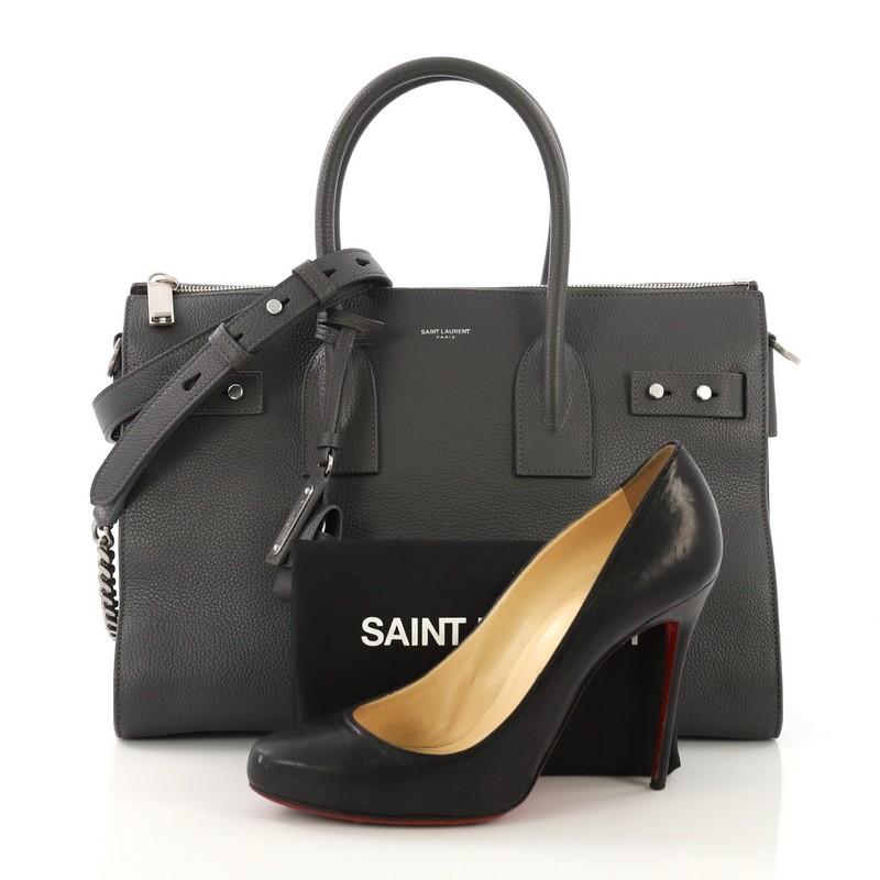 This Saint Laurent Sac de Jour Souple Zip Tote Leather Small, crafted from gray leather, features dual rolled leather handles, leather base feet, leather tabs threaded through side gussets, and silver-tone hardware. It opens to a black fabric