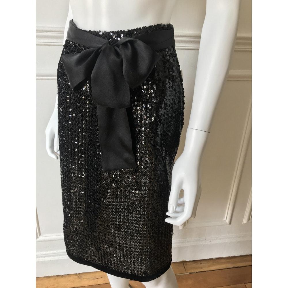 SAINT LAURENT Rive Gauche, Made in France, circa 80's. 
Mid-length black skirt embroidered with sequins. A large satin ribbon folds down on the front to make a knot. Zipper on the side finished with a metal clip. Very good condition. 
Tag size it