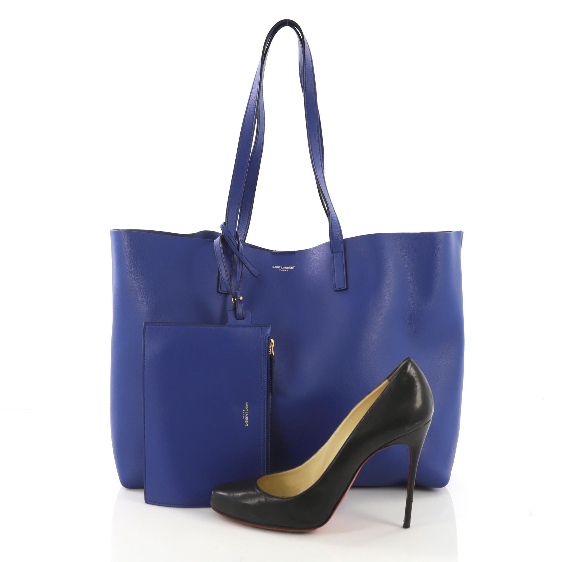 This Saint Laurent Shopper Tote Leather Large, crafted from blue leather, features dual flat leather handles, stamped logo at its center, and gold-tone hardware. Its magnetic snap closure opens to a blue raw leather interior. **Note: Shoe