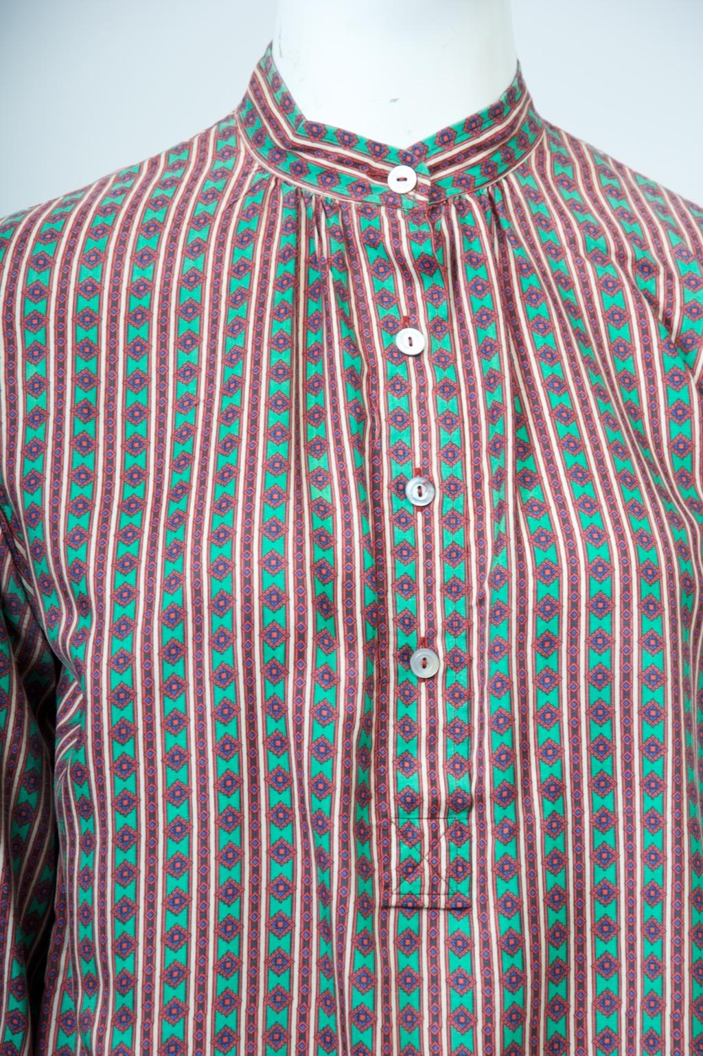 Saint Laurent Rive Gauche Bluse aus einem kleinen, geometrischen, vertikal ausgerichteten  Seidendruck in überwiegend grüner Farbgebung mit Kontrasten in Dunkelblau, Orange und Elfenbein. Die Bluse wird über den Kopf gezogen und hat einen