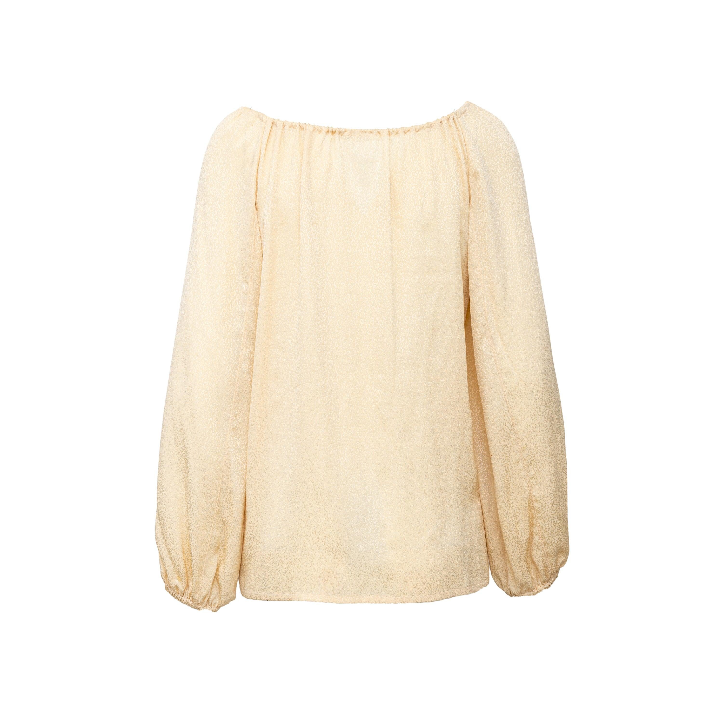 Made from high-quality silk, this Saint Laurent Rive Gauche top features a beautiful beige color with small paisley patterns. The tasselled ribbon tie on the neckline allows for adjustable styling, and the long elastic hemmed sleeves add a touch of