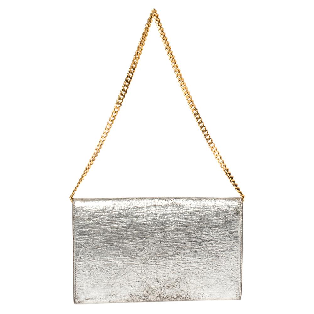 This Saint Laurent clutch is crafted from silver leather. It has a simple silhouette and features a gold-tone logo detailing on the front flap. With a fabric and leather interior, the clutch houses a zip pocket and multiple card slots. It is held by