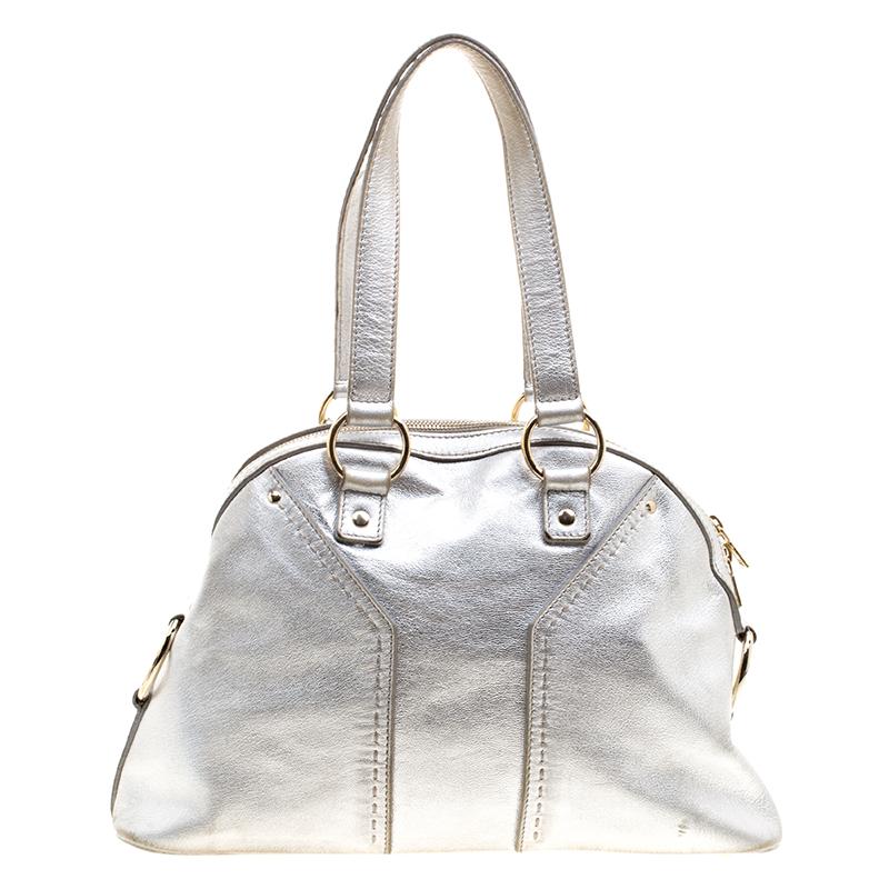 This Saint Laurent Muse satchel is perfect for everyday use. It has been meticulously crafted from leather and enhanced with gold-tone hardware. This silver satchel has two handles and a zipper which opens to a roomy satin interior capable of