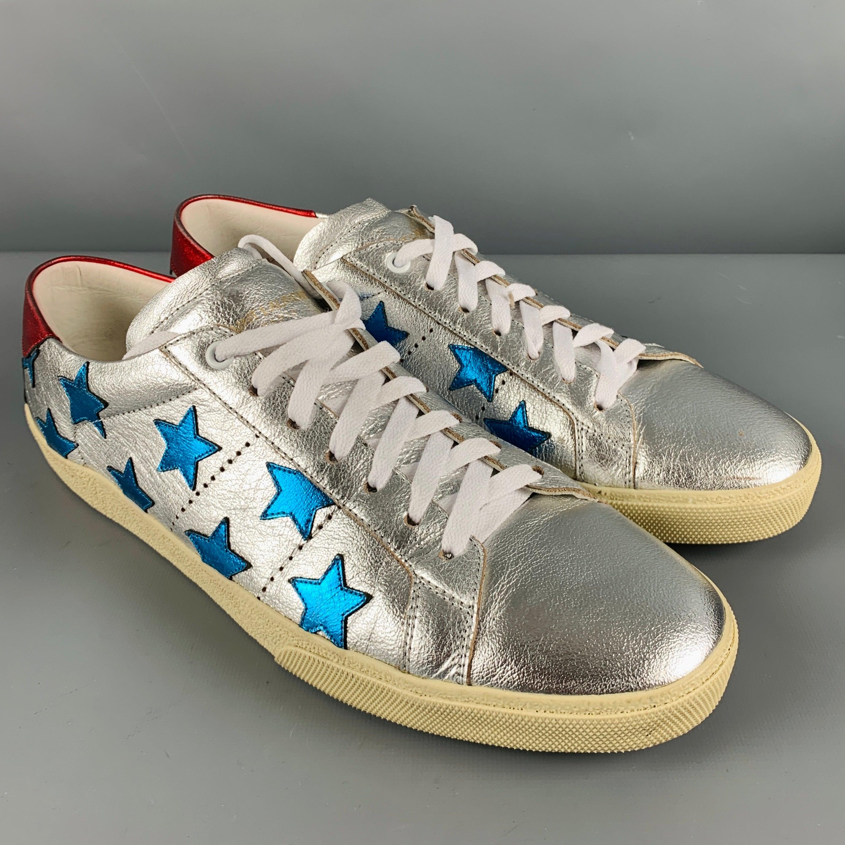 SAINT LAURENT sneakers
in a 
metallic silver leather fabric featuring a low top style, blue star appliques, red heel detail, and lace-up closure. Comes with dust bag and box. Made in Spainches Very Good Pre-Owned Condition. Minor signs of wear.