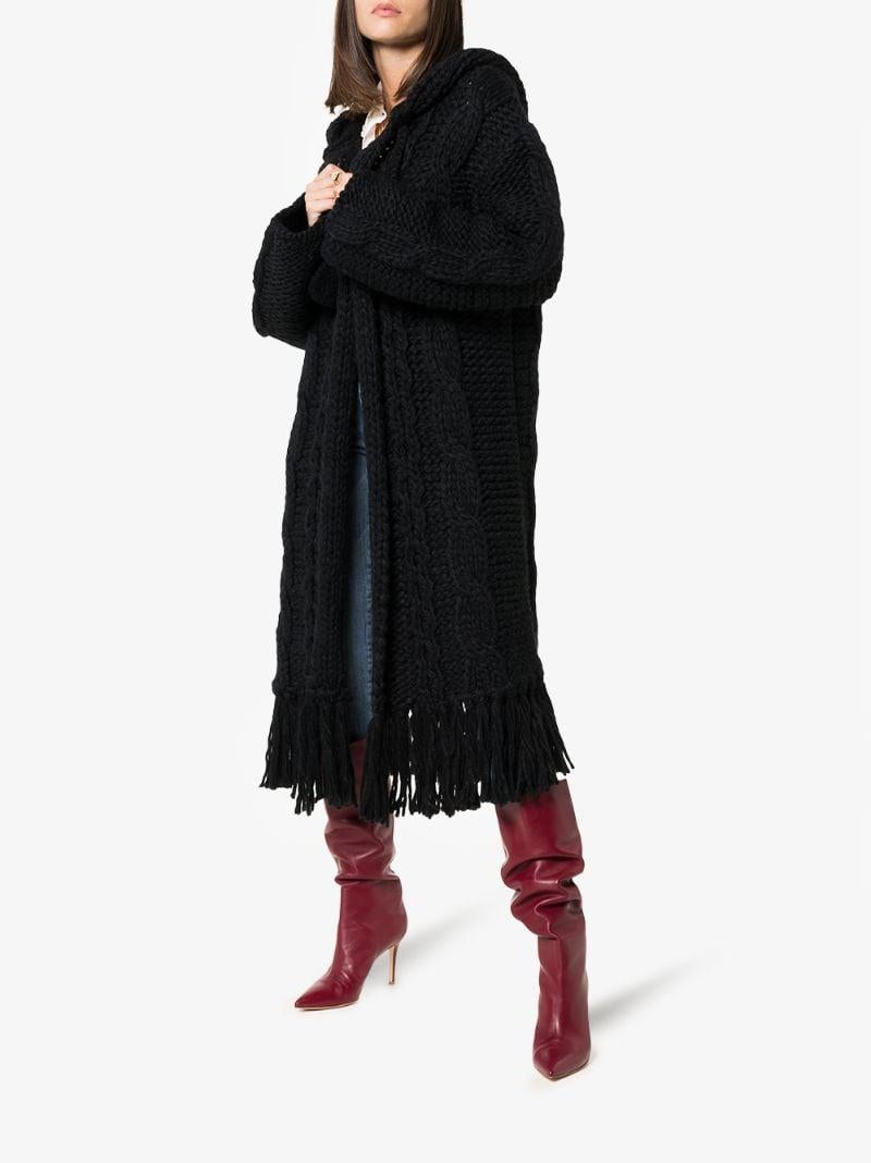 SAINT LAURENT oversized coat comes in a black wool blend chunky knit material featuring a cable knit design, hood with pom pom drawstrings, open front and fringe mid-length hem. Made in Italy.Very Good Pre-Owned Condition. Moderate signs of wear.